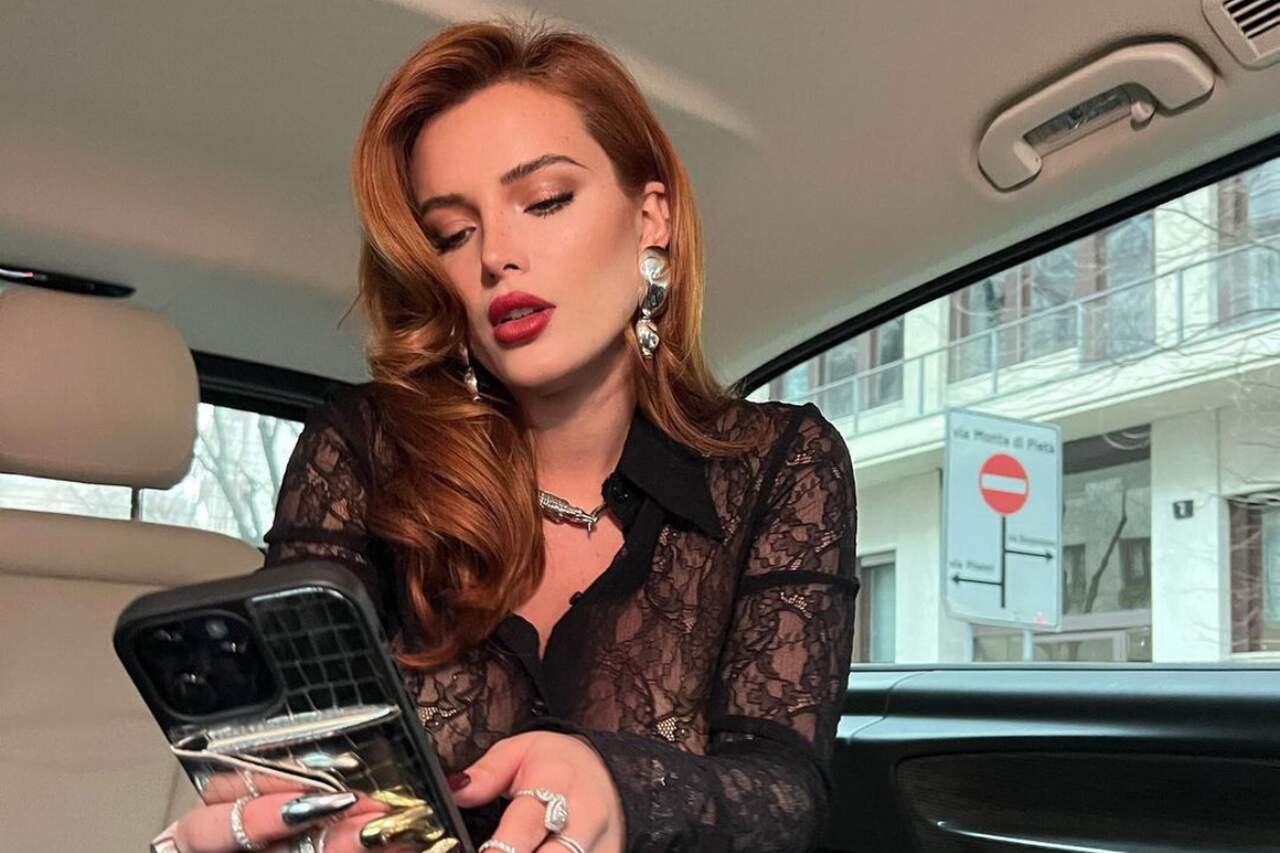 Bella Thorne vestida de preto com celular na mão