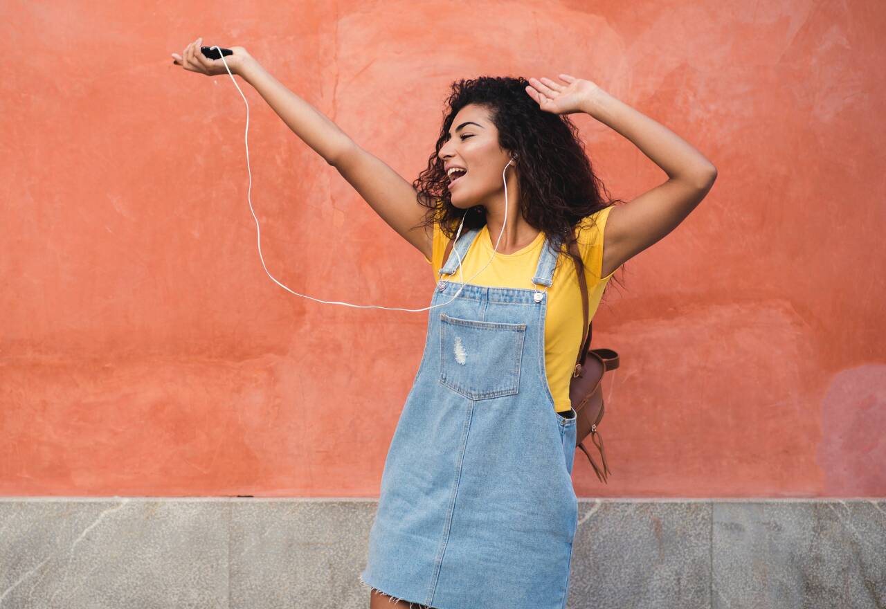 menina feliz ouvindo música no celular